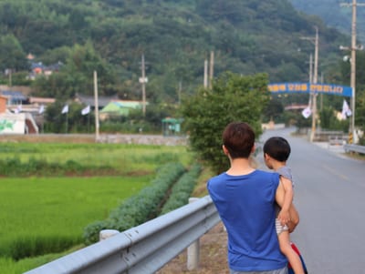 A family standing at the entrance of a village, seen from behind